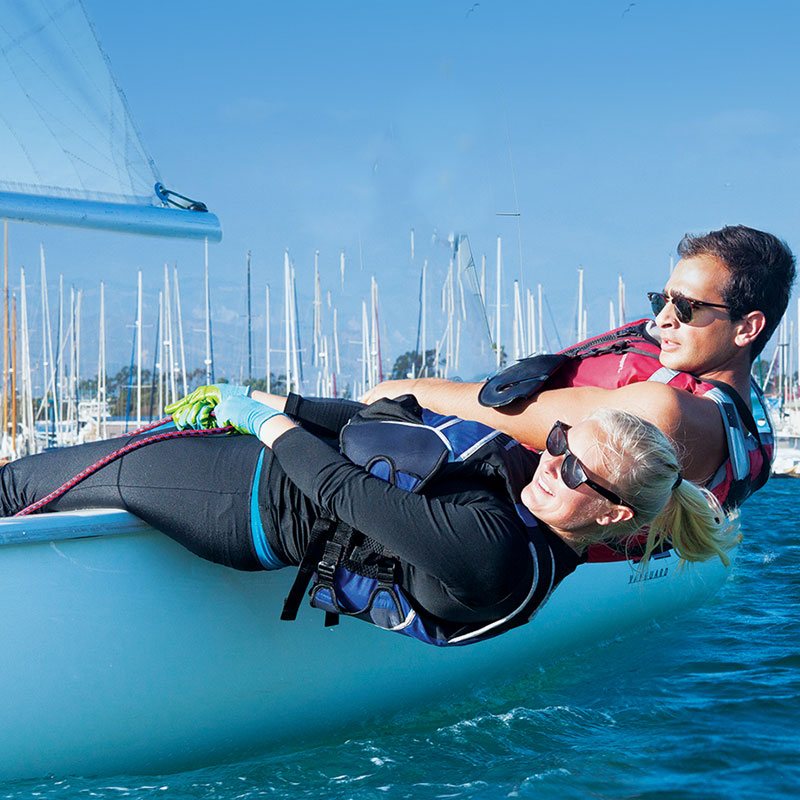 An instructor assists a student in hiking their sailboat