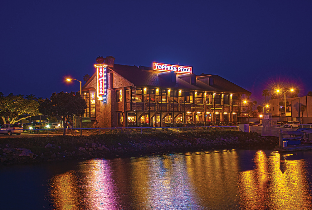 Toppers Pizza's big neon signs, lit up at night and reflected on the water