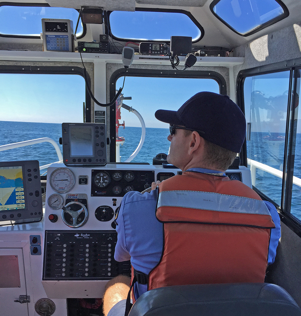 A Ventura County Harbor Patrol officer sits at the wheel of a patrol boat