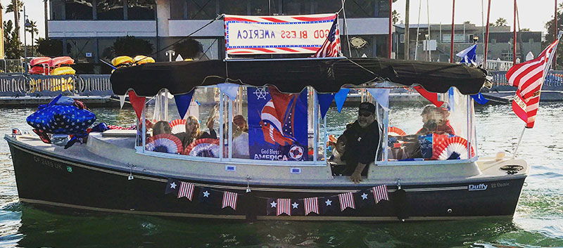 A Duffy boat decorated in red-white-and-blue for the Electric Boat Parade on the 4th of July