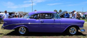 A glossy-purple classic Chevrolet with its hood popped