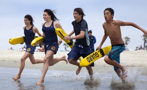 4 teens race to the water carrying rescue buoys