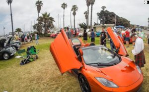 A sporty orange Tesla with its doors raised at the Central Coast British Car Club show
