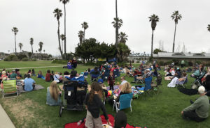 A crowd gathers on the lawn with blankets and lawnchairs for Fairy Tales in the Park
