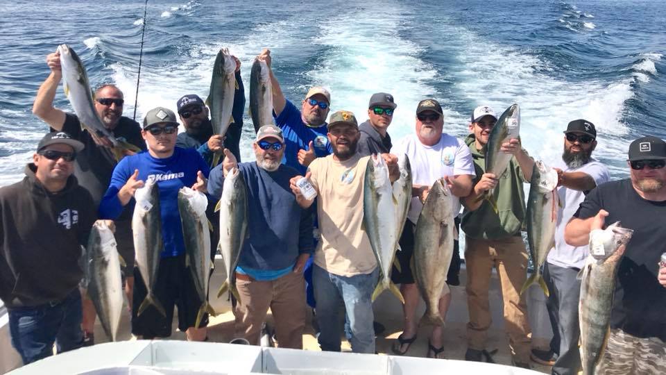 A large group of sportfishers hold up their catch of yellowfin tuna on the stern of their charter