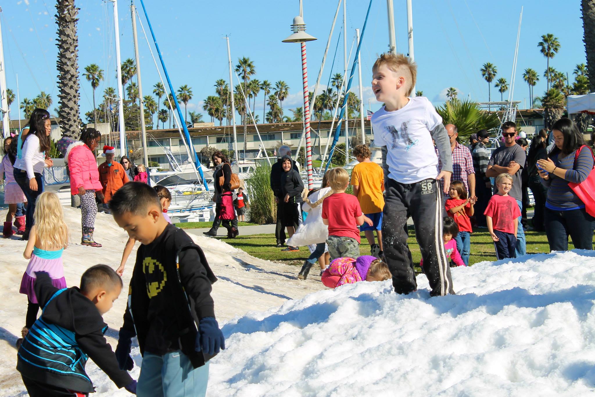 A crowd of children plays on piles of freshly-made snow in the harbor park