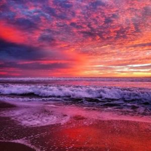 A dark, fiery red and purple sunset over the Pacific