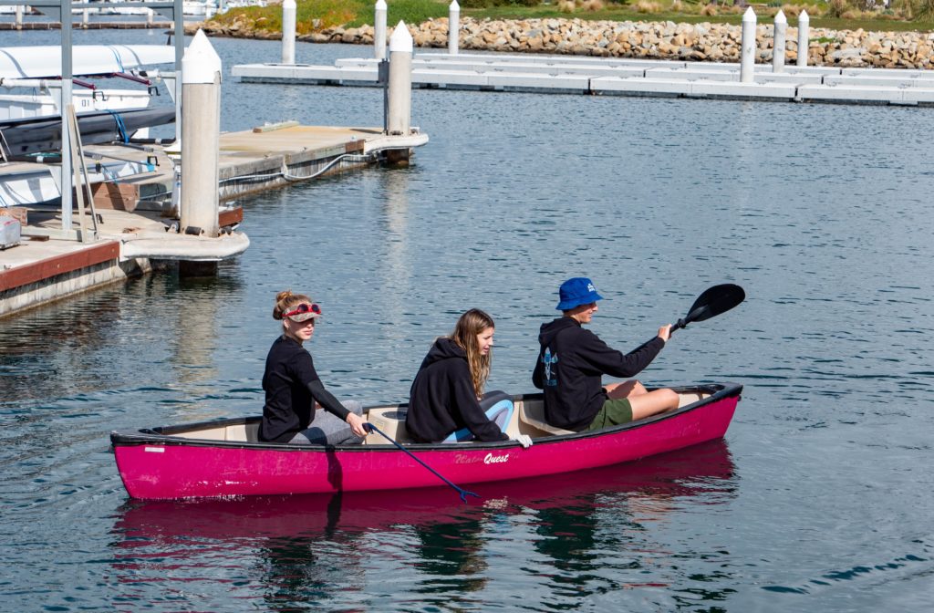 CIH Rowing Club members paddle a canoe during harbor cleanup