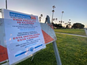 A sign warns visitors about harbor park closures due to covid-19